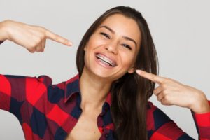 una mujer sonriendo felizmente con aparatos ortopédicos y sin llagas en la boca