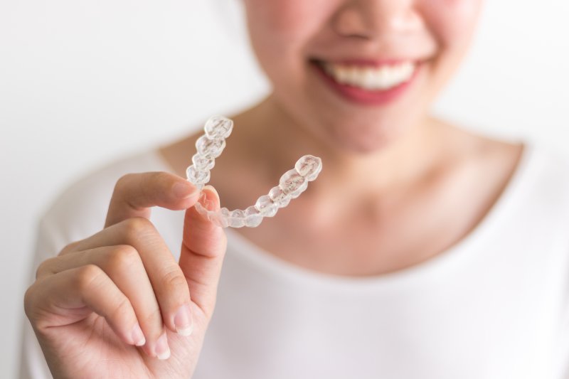 persona sosteniendo Invisalign y sonriendo